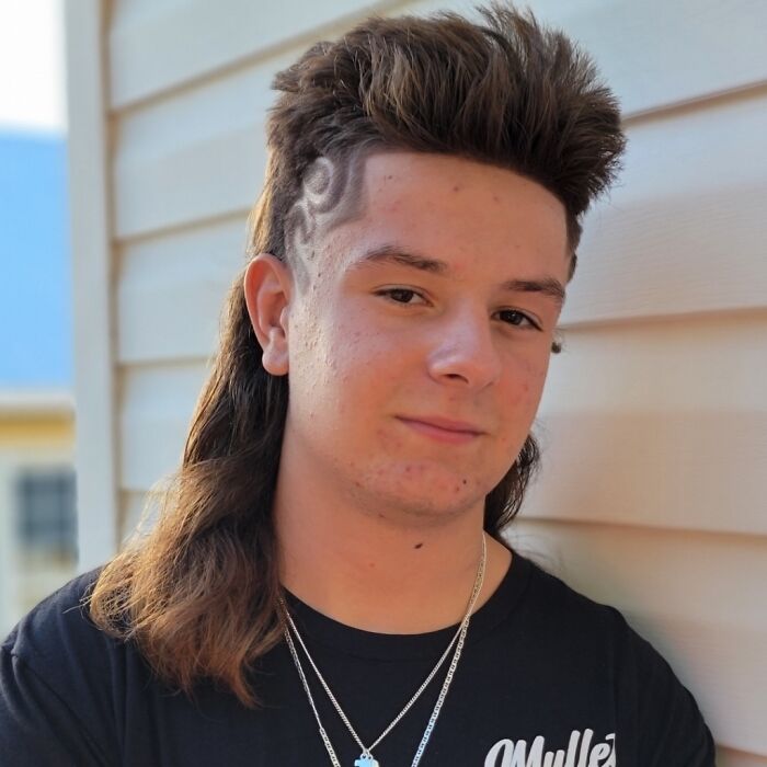 Young person with a stylish mullet hairstyle, showcasing a classic "business in the front, party in the back" look.