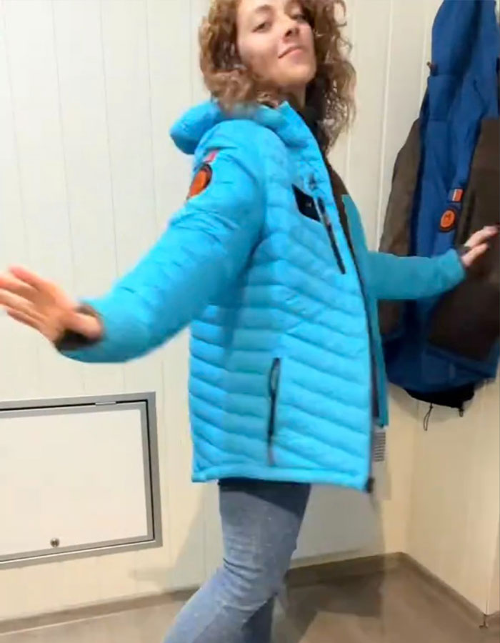 Spanish nurse wearing a blue jacket showcasing her Norwegian secret to staying warm indoors.