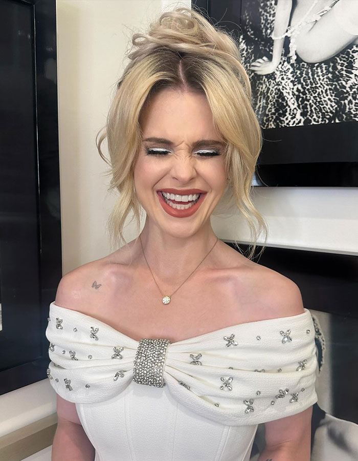 Smiling woman in an off-shoulder dress, representing Hollywood beauty trends and Ozempic discussion.