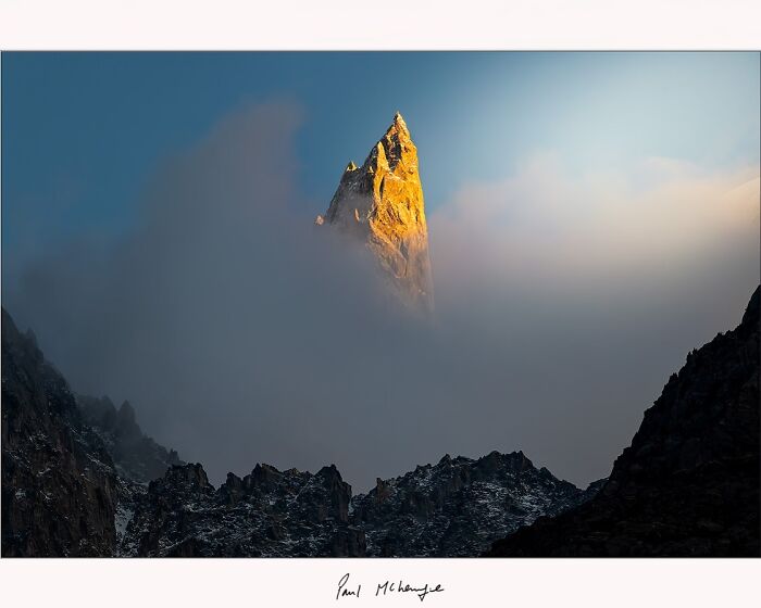 Mountain peak emerging from mist at sunrise, photographed by Paul McKenzie.