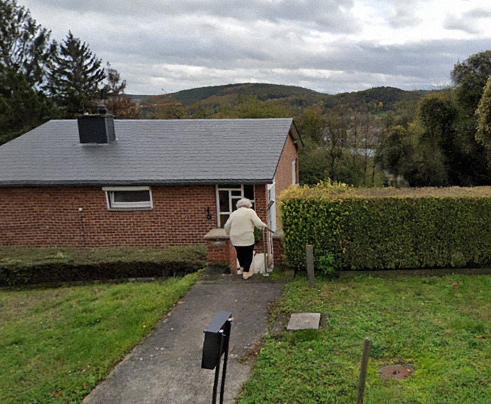 Paulette Landrieux walking towards a brick house, seen from the back, on a cloudy day—a scene related to mystery of her vanishing.