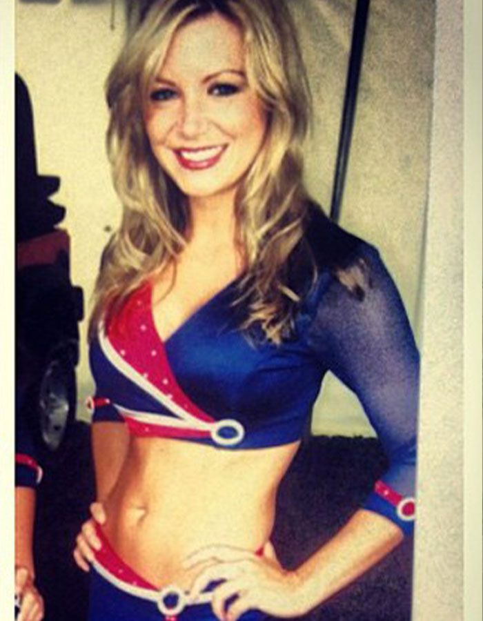 Former Buffalo Bills cheerleader in uniform, smiling, with hands on hips.