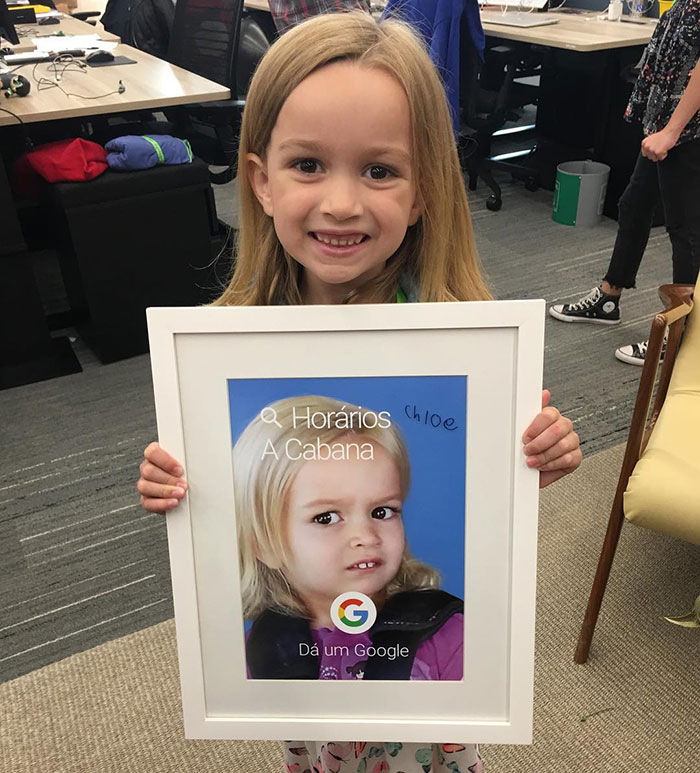 Girl holding a framed image of "Side-Eyeing Chloe" meme in an office setting.