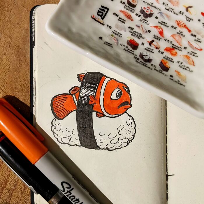 Funny drawing of a clownfish on sushi by Ed Harrington, with markers nearby and a sushi menu in the background.