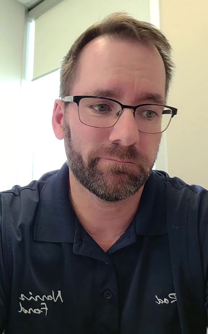 Canadian dad sharing lottery win advice, wearing glasses and a navy shirt, seated in a well-lit room.