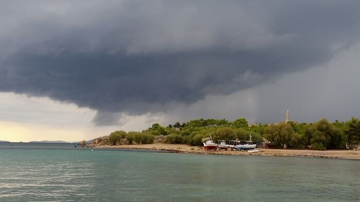 Dark storm cloud over a coastal shore, showcasing stunning natural phenomena.