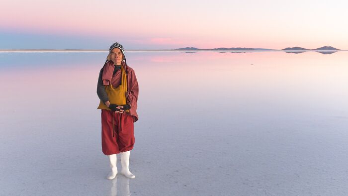 Person standing on reflective salt flat at sunset, showcasing incredible natural phenomena.