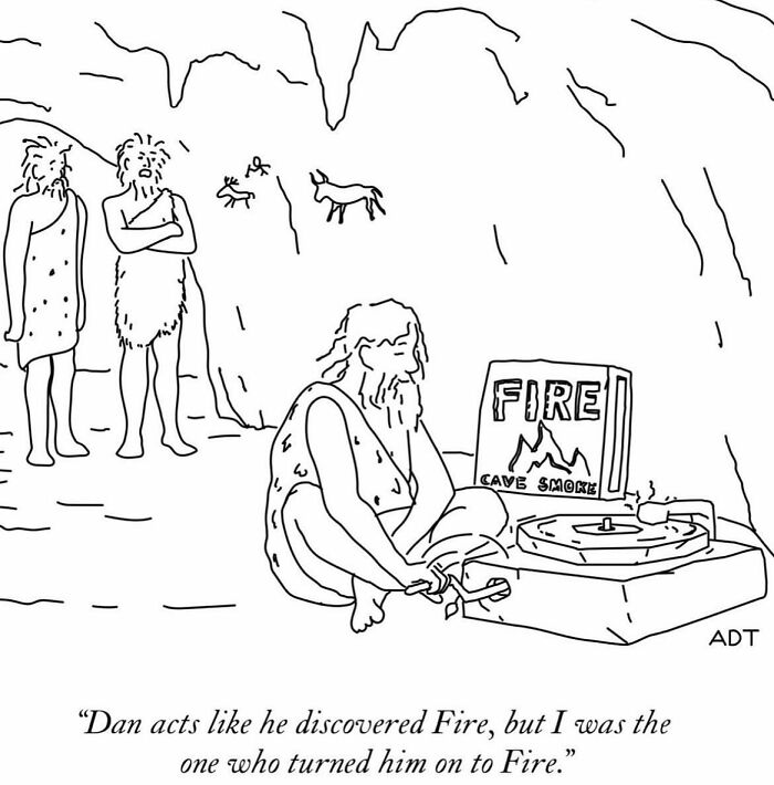 Cavemen humor: one listens to a record player labeled "Fire," while others watch skeptically in a cave.