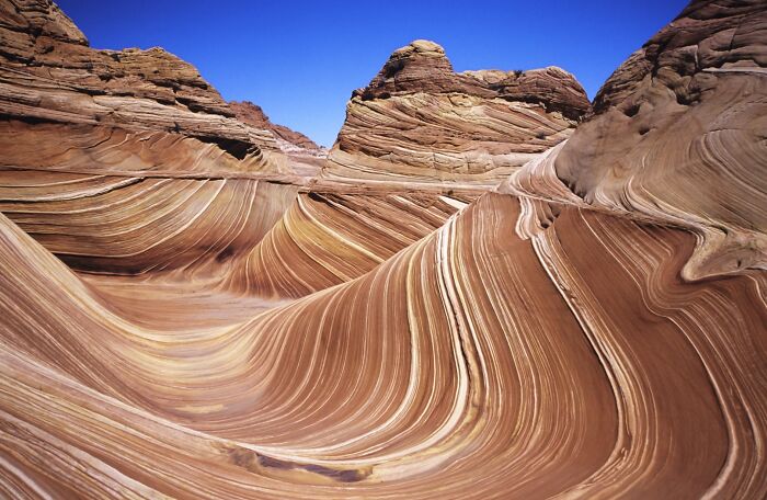 Stunning natural phenomena of swirling rock formations under a clear blue sky.