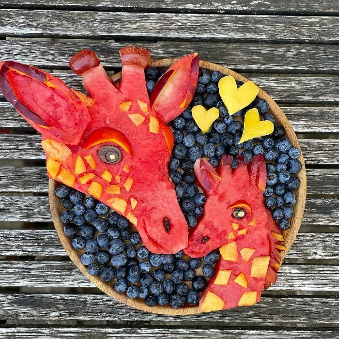 Fruit art featuring giraffes made from watermelon and peaches surrounded by blueberries.