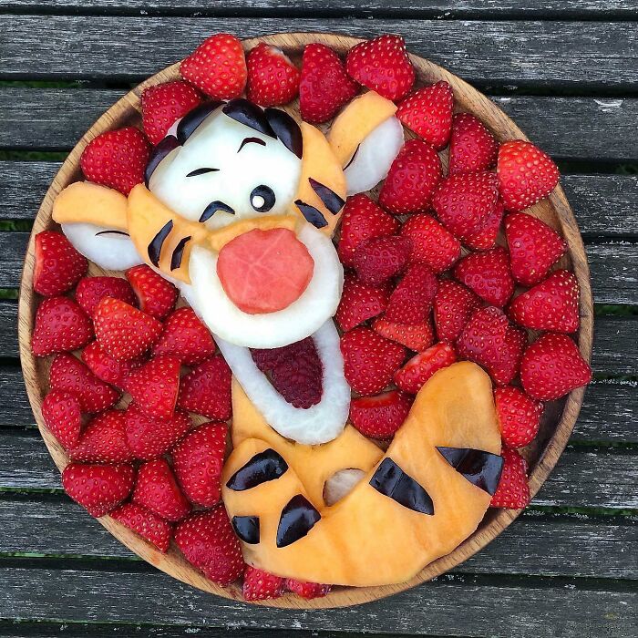 Artistic fruit arrangement of a tiger face with strawberries showcasing healthy eating.