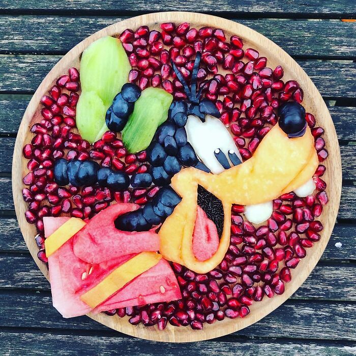 Fruity artwork of a cartoon character on a wooden plate, showcasing healthy eating creativity.