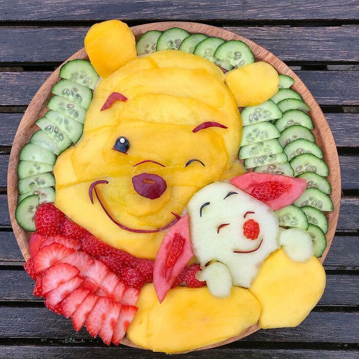 Healthy eating art featuring fruit and vegetable characters on a wooden plate, showcasing creativity in food presentation.