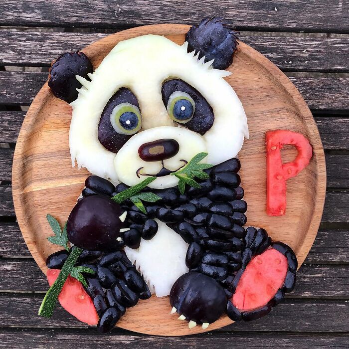 Healthy eating art: a panda crafted from fruits on a wooden plate.