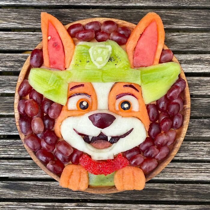 Healthy eating artwork featuring a character made from fruits on a wooden table.