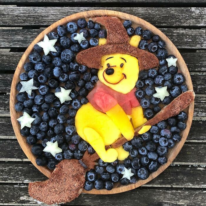 Healthy eating art: fruit arranged as a character on a plate with blueberries and star-shaped fruit details.