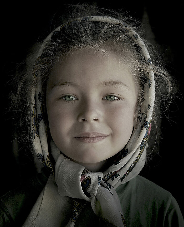 Young girl with a gentle smile and a patterned headscarf, captured in a portrait symbolizing resilience and beauty.