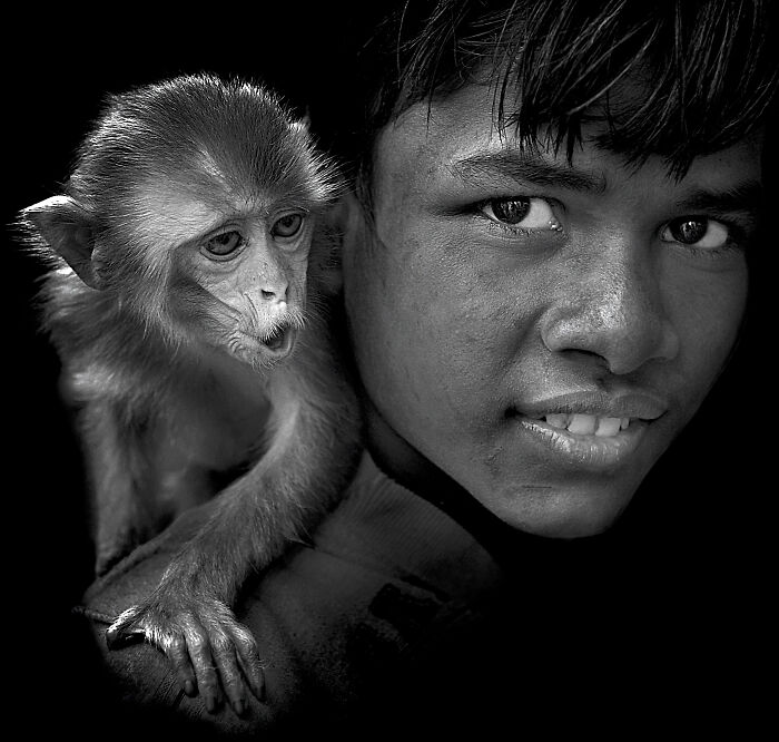 A boy and a monkey share a close moment, capturing the resilience and beauty of everyday people.