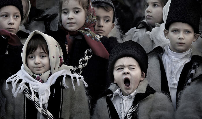 Children in traditional clothing, one yawning, showcasing everyday people's resilience and beauty.