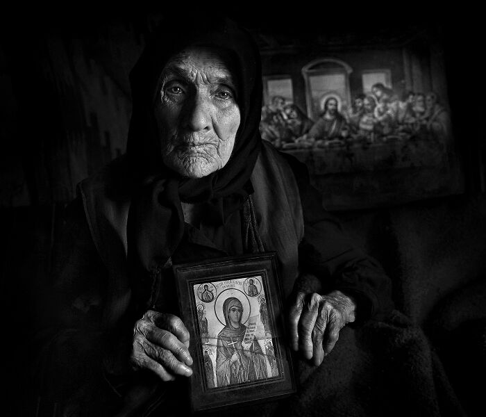 Elderly woman holding an icon, showcasing the resilience and beauty of everyday people in Istvan Kerekes' photography.