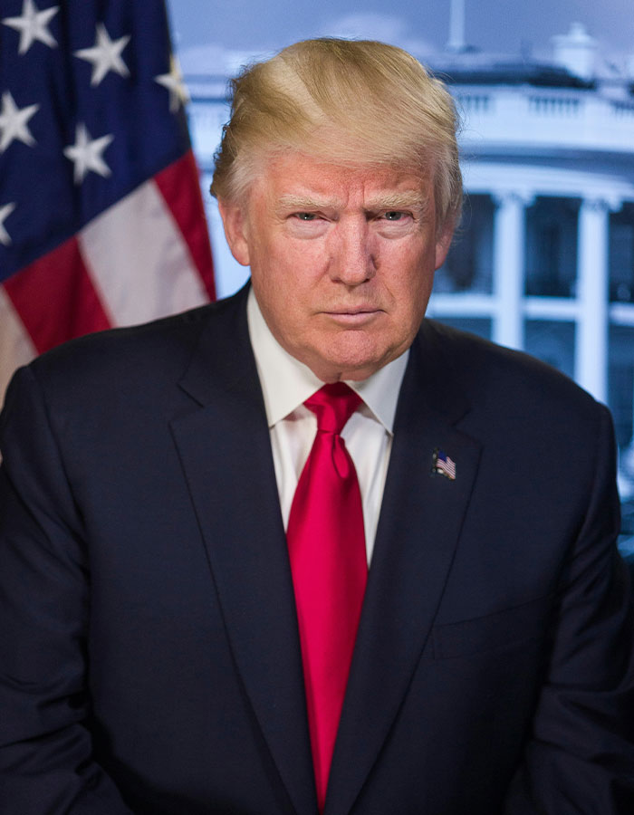 Man in suit and red tie in front of a blurred background with a flag, relevant to TikTok ban law discussion.