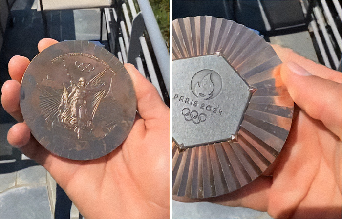 Close-up of hands holding a Paris 2024 Olympic medal, displaying both front and back engravings.