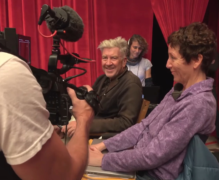 Fans remember 'Twin Peaks' director David Lynch, smiling during a behind-the-scenes moment with his crew.