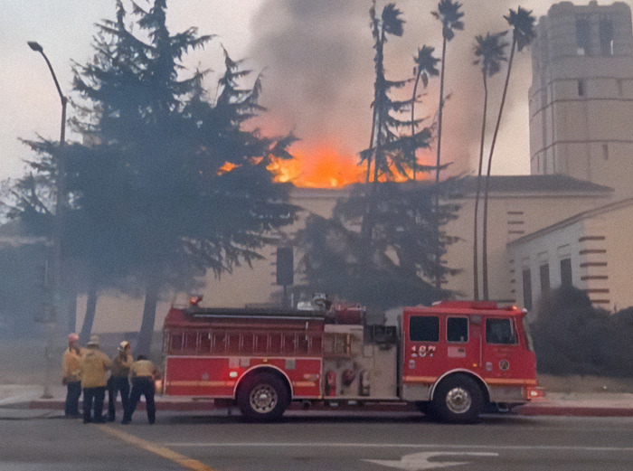 Firefighters with truck at building fire, addressing criticism over female firefighter leaders.