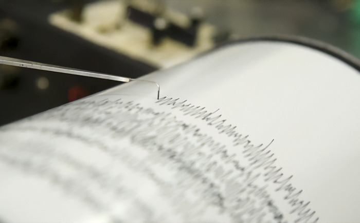 Seismograph needle recording earthquake data, highlighting predictions and analysis of seismic activity.