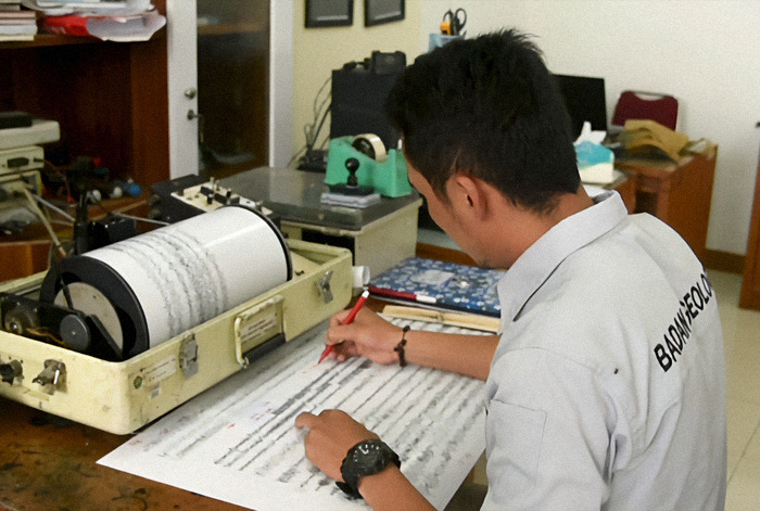 Expert analyzing earthquake data with seismograph.