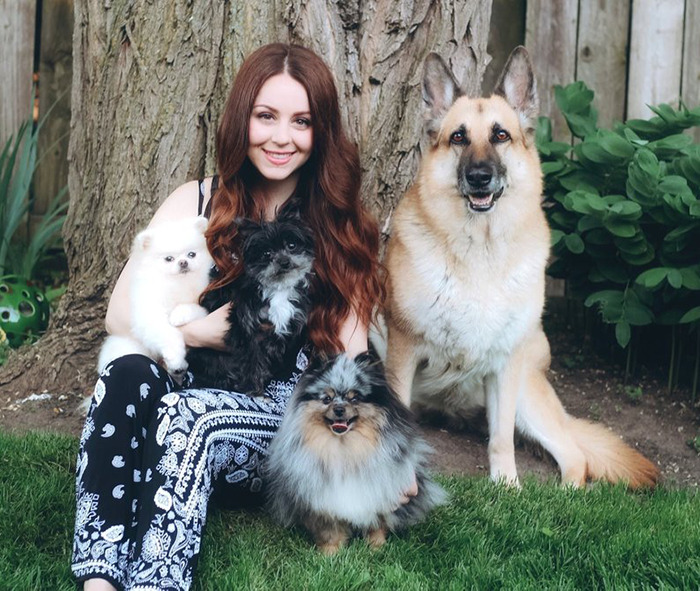 Pet groomer Vanessa De Prophetis sitting outside with four happy, well-groomed dogs.