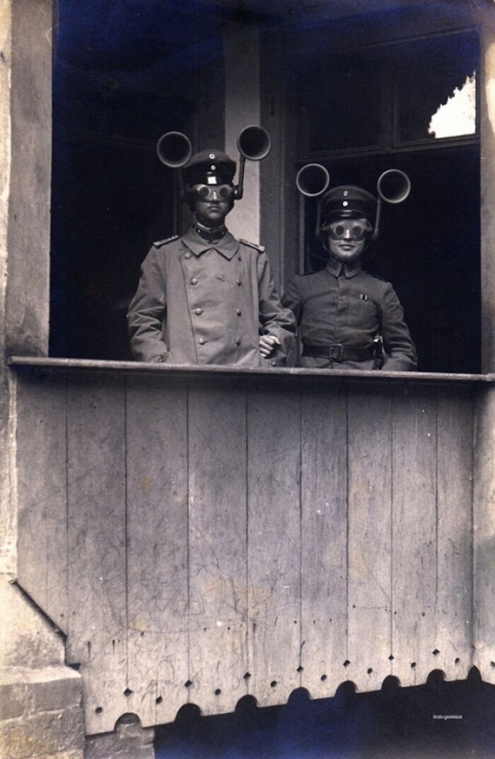 Two people in historical military uniforms wearing early hearing devices, showcasing historical inventions.