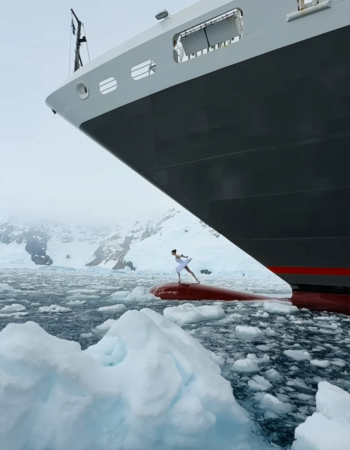 Ballerina dances on ship's bow in Antarctica, amidst icy waters, showcasing career-ending danger.