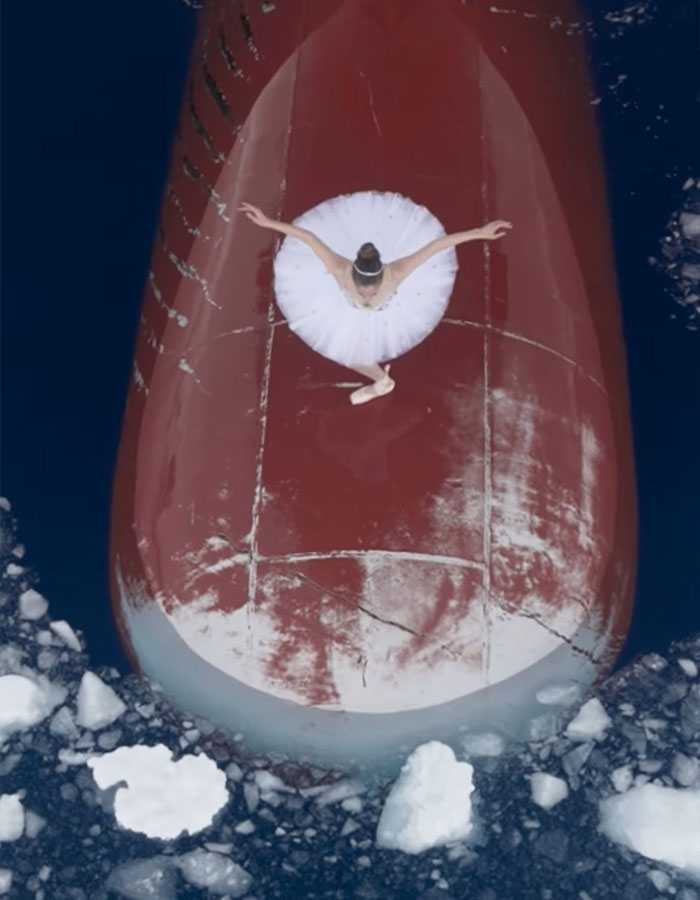 Ballerina performing on ship's bow in Antarctica, surrounded by icy waters, showcasing career-ending danger.