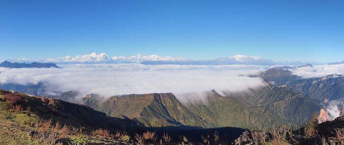 Panoramic view of stunning natural phenomena with mountains and clouds under a clear blue sky.