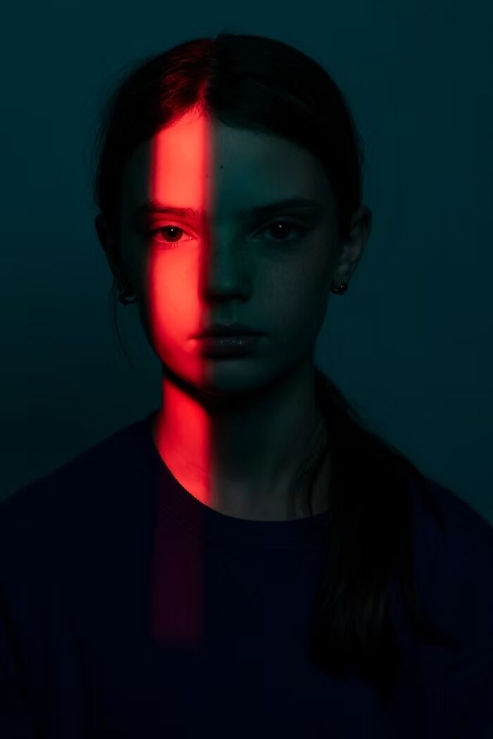 Portrait of a girl with half her face highlighted in red light, a winning photo from The Artist Gallery Awards.