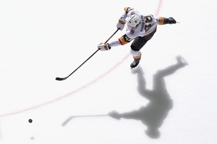 Hockey player in action on ice, casting a shadow, showcasing sports photography excellence.