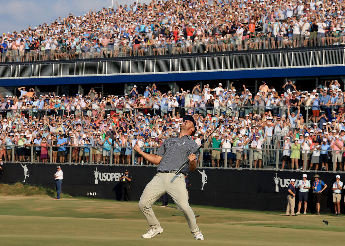 Golfer celebrates passionately on the green in front of a large crowd, showcasing sports photography excellence.