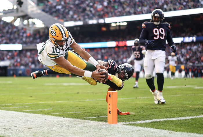 Football player dives over opponent for touchdown, showcasing skill and athleticism at the 2025 World Sports Photography Awards.