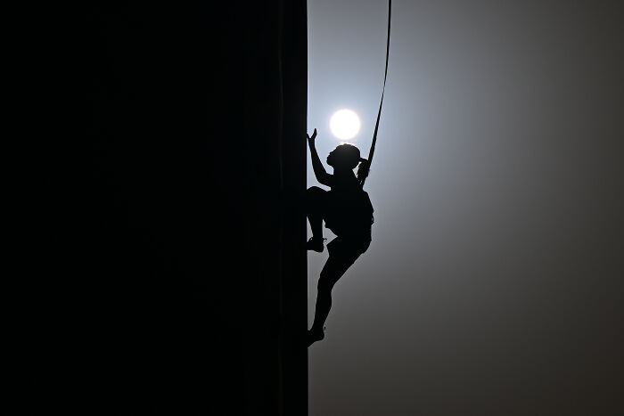 Silhouetted climber against sunset, capturing an award-winning sports photography moment.