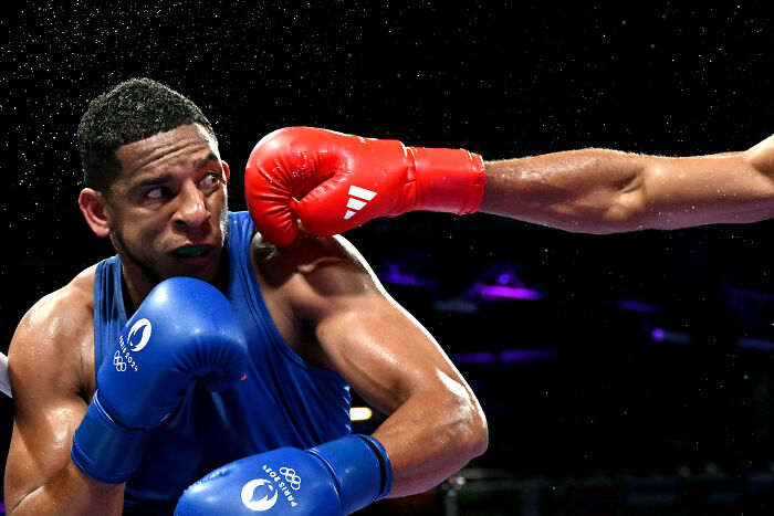 Boxer dodges a red-gloved punch during a match, capturing intense action from World Sports Photography Award winners.