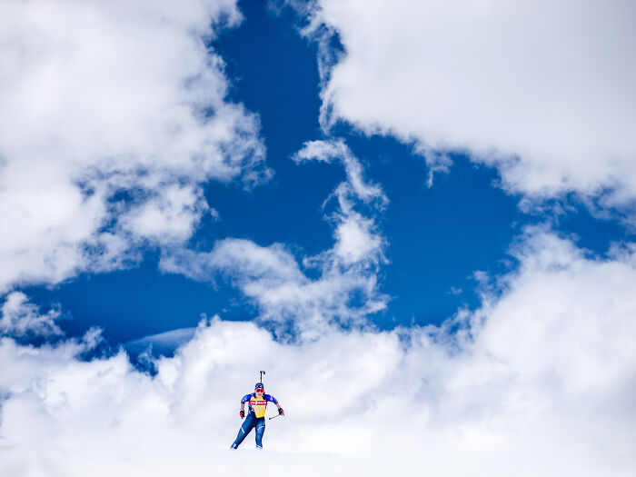 Skier against a vivid blue sky with clouds, showcasing sports photography award winners 2025.