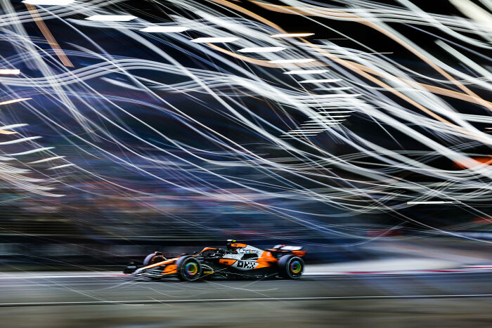 Race car speeding on track at night with dramatic light trails, captured by 2025 World Sports Photography Award winner.