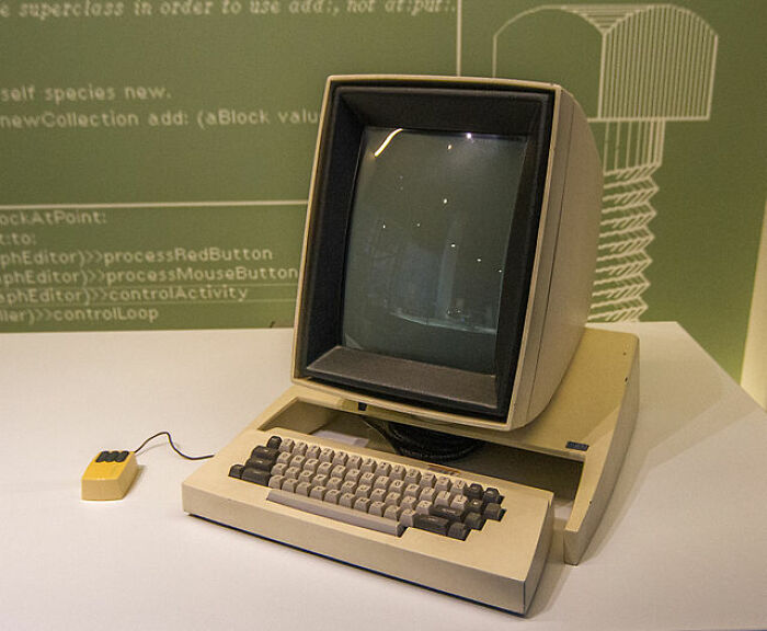 Vintage computer showcasing historical inventions with a CRT monitor, keyboard, and yellow mouse.