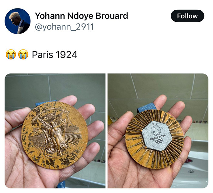 Athlete holding a 1924 Paris Olympic medal in hand, featuring intricate designs on the front and back.