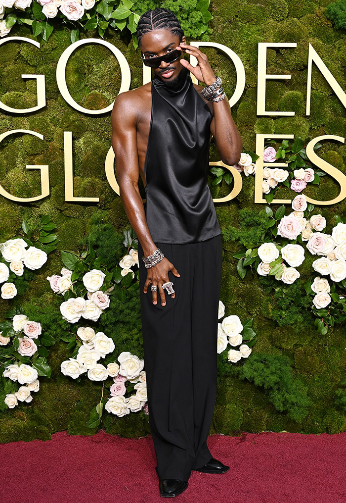 Person in a stylish black outfit poses confidently on the red carpet at the Golden Globes 2025.