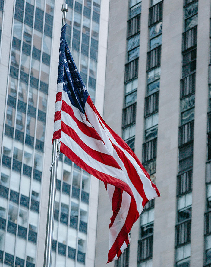 American flag waving in front of a tall building, symbolizing patriotism.