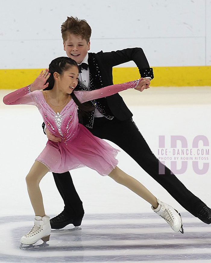 Child ice skating duo performing in colorful costumes on the rink.