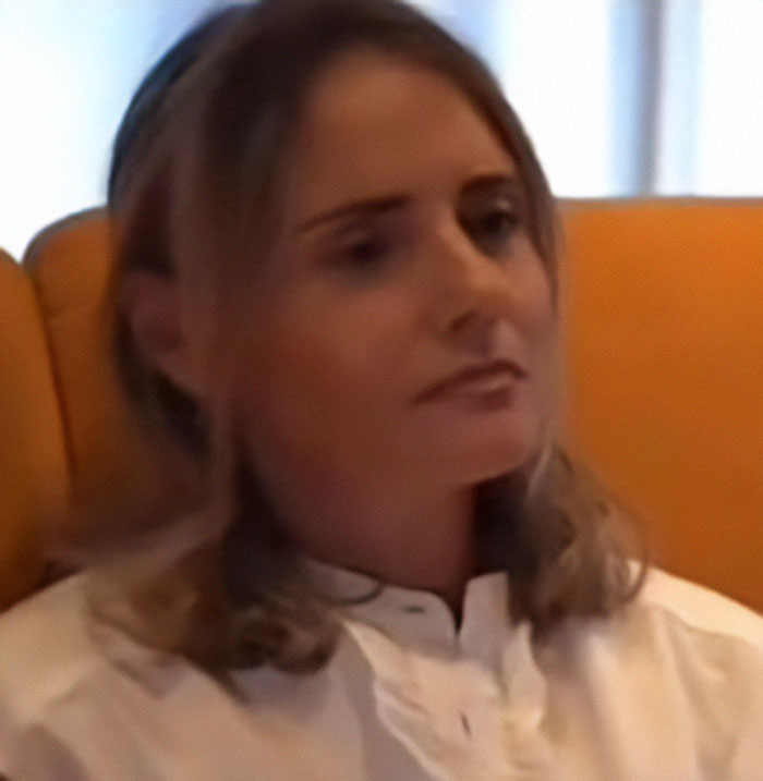 Woman affected by Fake AI Brad Pitt scam sits on a yellow sofa, reflecting on financial fraud.