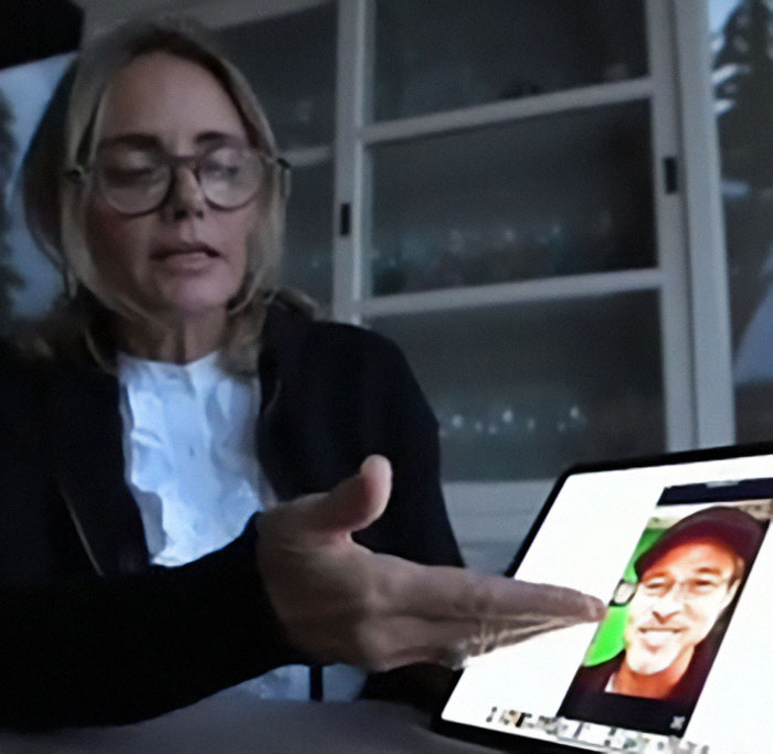 A woman gestures at a tablet displaying an image linked to Brad Pitt's AI scam warning.